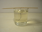 leg de satéprikker op het glas, zodat het garen in het suikerwater hangt