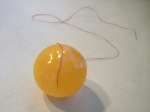 plak de ene kant van het garen met plakband aan de pingpongbal