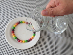 schenk een dun laagje water op het bord, zodat alle skittles in het water liggen